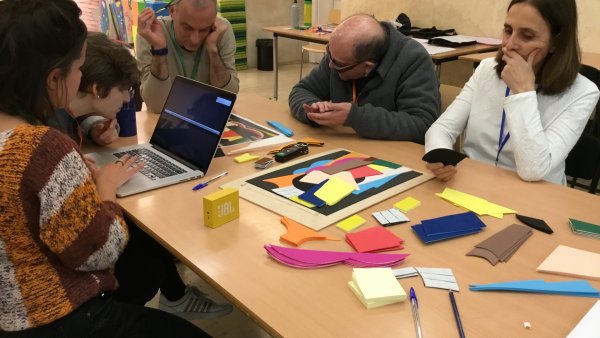 Personas junto a una mesa con formas recortables y ordenador